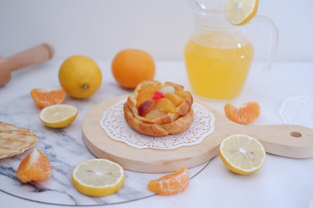 Crostata al limone fatta in casa con frutta fresca e succo d'arancia su sfondo bianco