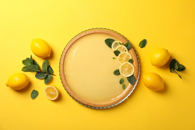 Crostata al limone, menta e limoni su giallo, vista dall'alto