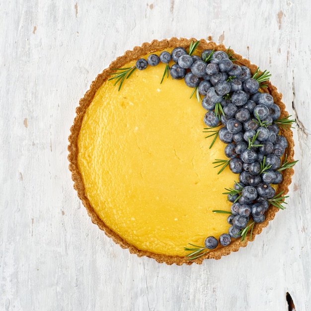 Crostata con cagliata di limone e mirtilli freschi su una superficie di legno chiaro.vista dall'alto