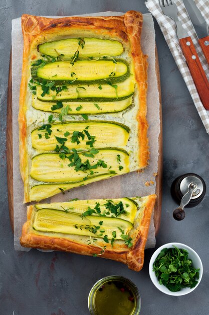 Crostata con zucchine, ricotta e prezzemolo su una superficie di cemento scuro. Vista dall'alto. Messa a fuoco selettiva