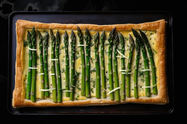 Crostata di asparagi su piatto nero con olio d'oliva spolverata di sale