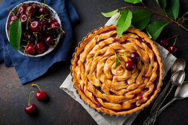 Crostata di ciliege casalinga con i frutti della ciliegia in una ciotola