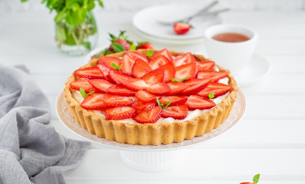 Crostata di fragole con crema pasticcera su un piatto su uno sfondo di legno bianco Copia spazio