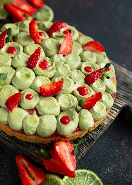 Crostata di frutta rotonda con fragole. pistacchi e lime sul tagliere di legno