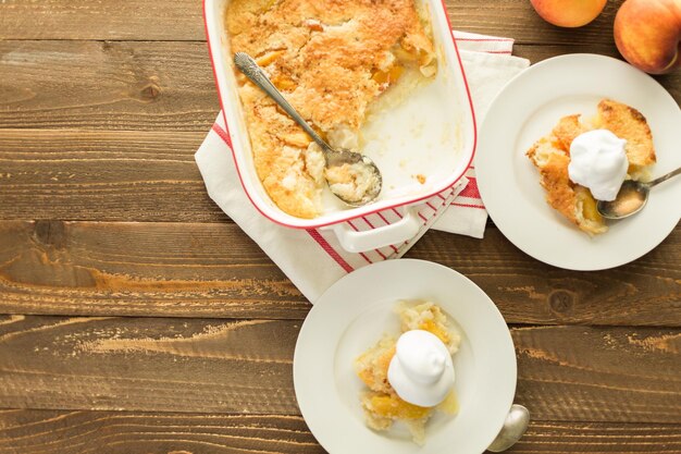 Crostata di pesche appena sfornate con pallina di panna montata.