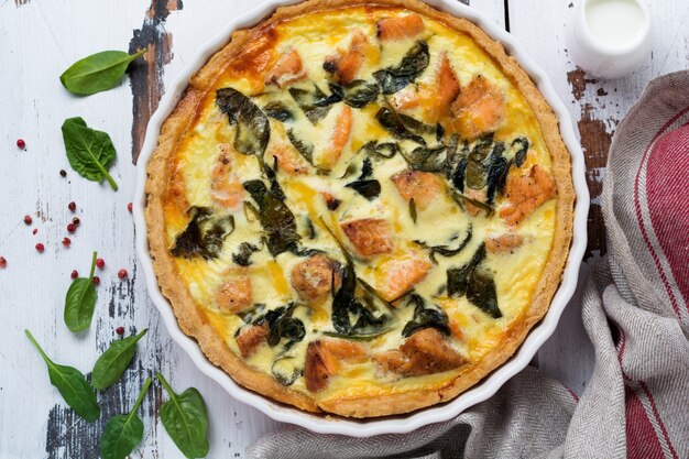 Crostata di quiche fatta in casa con pesce rosso e spinaci su luce