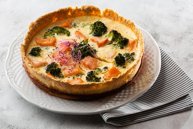 crostata di quiche, vista dall'alto. vista dall'alto. Classica quiche di salmone e broccoli a base di pasta frolla con cimette di broccoli e salmone affumicato in un cremoso primo piano di crema pasticcera all'uovo sul tavolo.