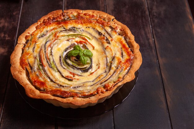 Crostata di verdure a spirale con zucchine, melanzane, carote su fondo di legno vista dall'alto piatta