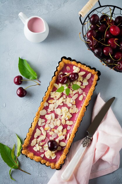 Crostata estiva con crema pasticcera alle ciliegie su deton grigio.