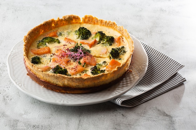 Crostata per quiche, vista dall'alto. vista dall'alto. Classica quiche di salmone e broccoli a base di pasta frolla con cimette di broccoli e salmone affumicato in un cremoso primo piano di crema pasticcera all'uovo sul tavolo.