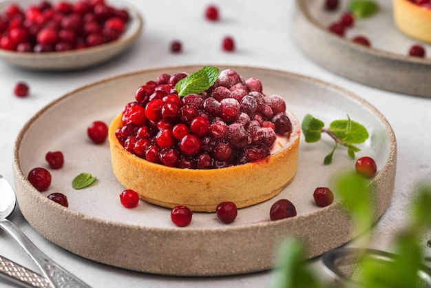 Crostate di frutti di bosco freschi con zucchero a velo di mirtillo rosso e menta in un piatto sul tavolo bianco Gustosi dessert da vicino