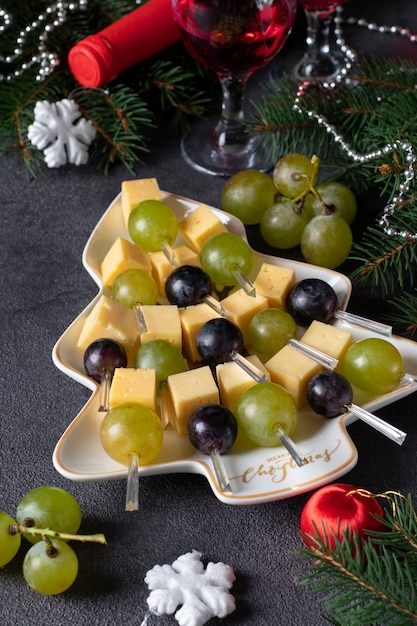 Crostini con formaggio e uva serviti nel piatto come albero di Natale, su sfondo grigio scuro. Spuntino per la festa di Capodanno