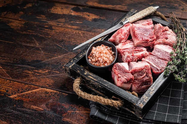 Crudo crudo cubetti di carne di agnello in vassoio di legno con sale e timo Sfondo di legno Vista dall'alto Spazio di copia