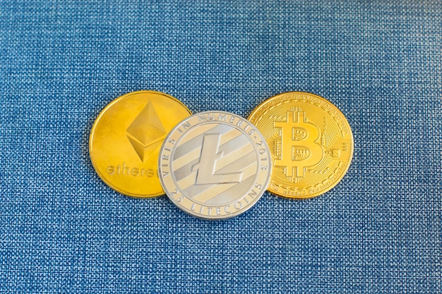 Crypto currency coin Bitcoin, Litecoin ed Ethereum monete in portafoglio in pelle su sfondo blu.