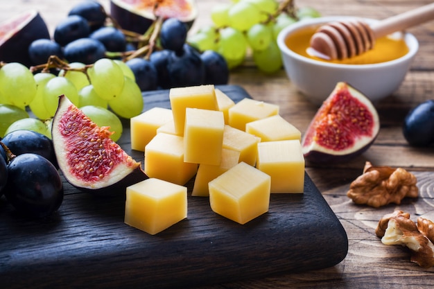 Cubetti di formaggio, fichi di frutta fresca uva Noce di miele su tagliere di legno. Messa a fuoco selettiva. Avvicinamento.