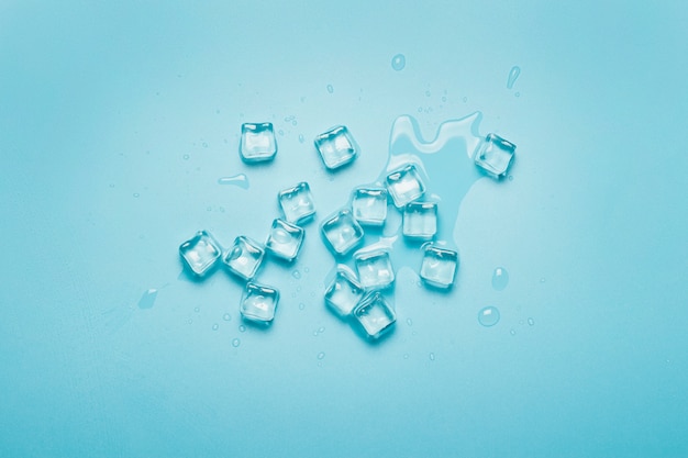 Cubetti di ghiaccio con acqua su una priorità bassa blu. Concetto di ghiaccio per bevande.