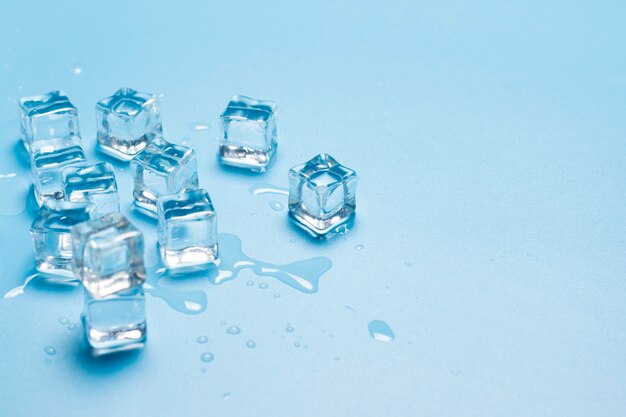 Cubetti di ghiaccio con acqua su una priorità bassa blu. Concetto di ghiaccio per bevande.