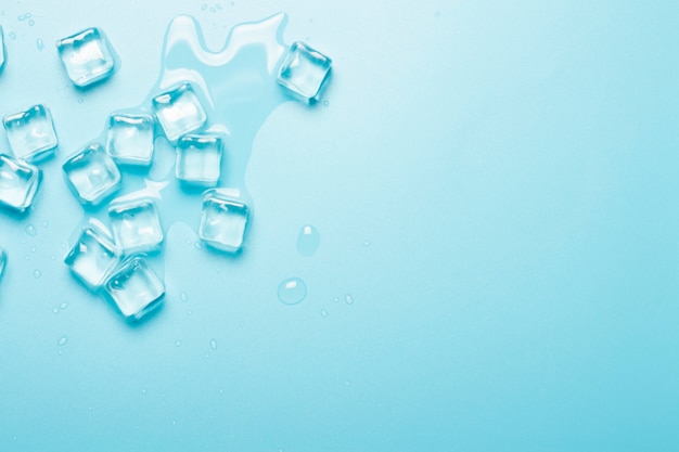 Cubetti di ghiaccio con acqua su uno sfondo blu. Concetto di ghiaccio per bevande.