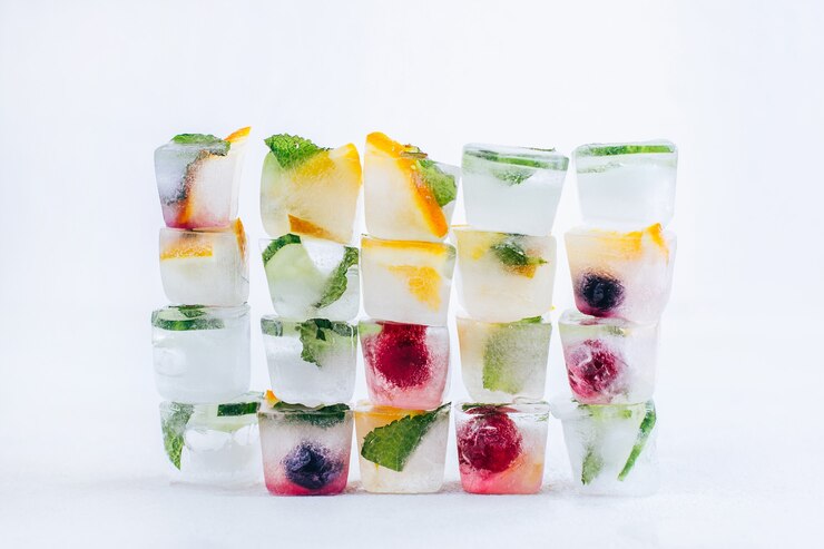 Cubetti di ghiaccio con frutta congelata e menta piramide stand su bianco