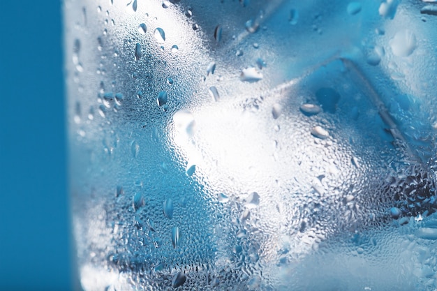 Cubetti di ghiaccio in un bicchiere appannato con gocce di acqua ghiacciata macro del primo piano