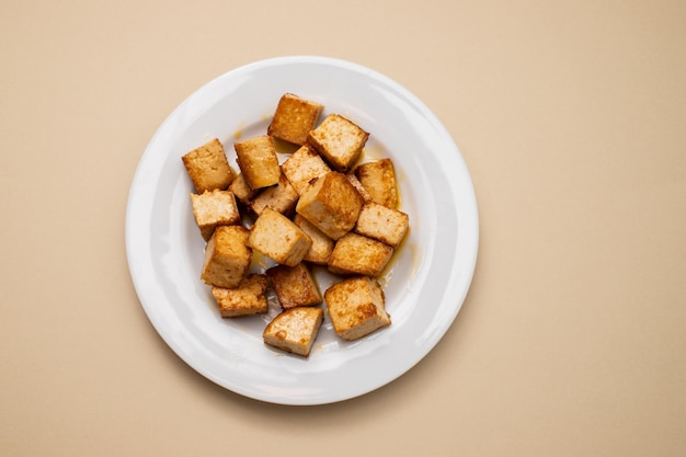 Cubetti di tofu fritti in padella croccanti su un piatto piccolo