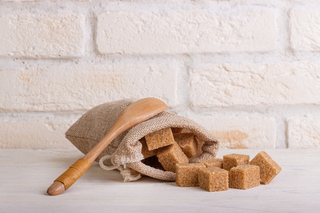 Cubetti di zucchero di canna in un sacchetto con un cucchiaio di legno