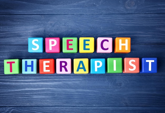 Cubi colorati con il testo SPEECH THERAPIST su sfondo di legno blu