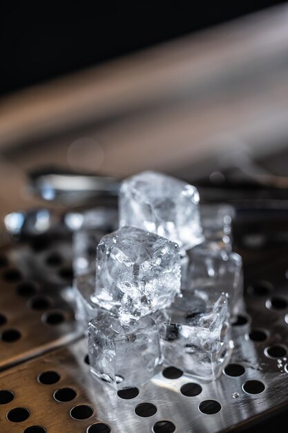 Cubi di ghiaccio cristallini sulla base in acciaio inossidabile del bancone del bar