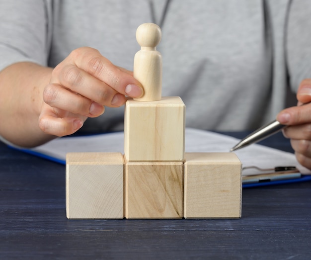 Cubi di legno a forma di scala e figurina di un uomo. concetto di crescita della carriera, raggiungimento degli obiettivi. Crescita personale, capo della società, CEO