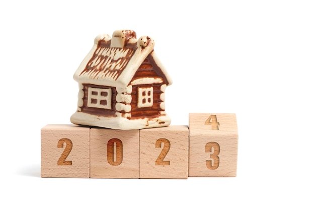 Cubi di legno con iscrizione 2023 che si trasforma in 2024 e casa su sfondo bianco
