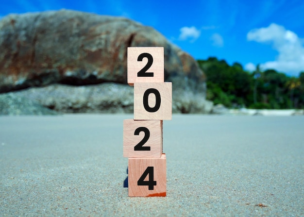 Cubi di legno con l'iscrizione "2024" e "Buon anno nuovo" sullo sfondo della sabbia della spiaggia