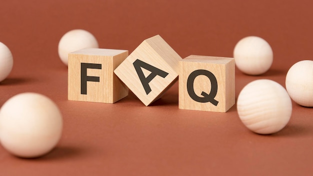 Cubi di legno con la parola FAQ su sfondo marrone vista frontale