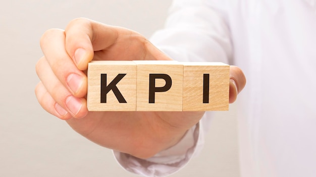 Cubi di legno con le lettere KPI sulla mano sullo sfondo bianco