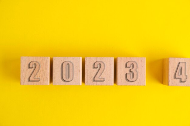 Cubi di legno con numeri 2023 sfondo giallo che diventano 2024