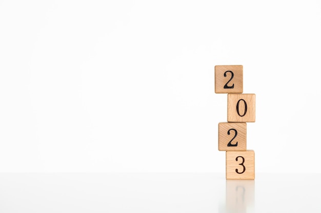 Cubi di legno con testo 2023 scritto in nero su una superficie di blocchi di legno Concetto di felice anno nuovo