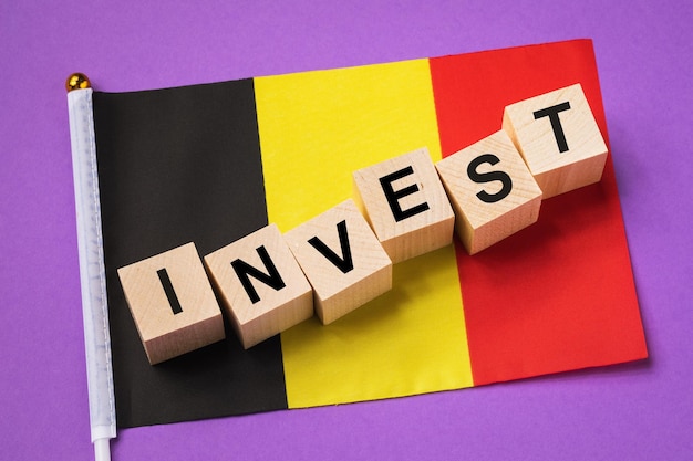 Cubi di legno con testo e una bandiera su uno sfondo colorato il concetto di investimento dal Belgio