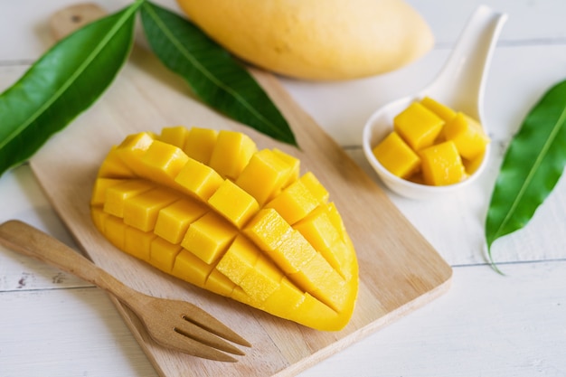 Cubi maturi del mango e del mango sulla tavola di legno bianca