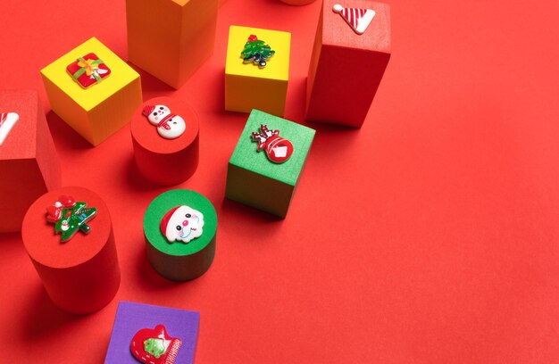 Cubi per bambini multicolori di peluche di diverse dimensioni con simboli di Natale sopra su di essi su sfondo rosso da vicino. Decorazioni natalizie. Vista dall'alto. Copia spazio per il testo.