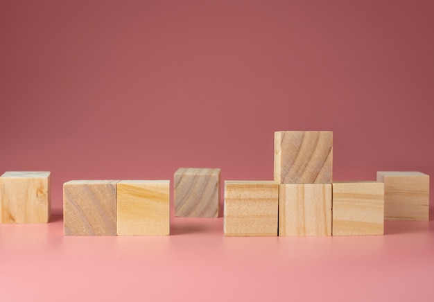 Cubo di legno su sfondo rosa.