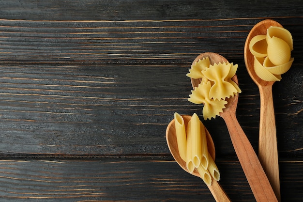 Cucchiai con pasta cruda su legno