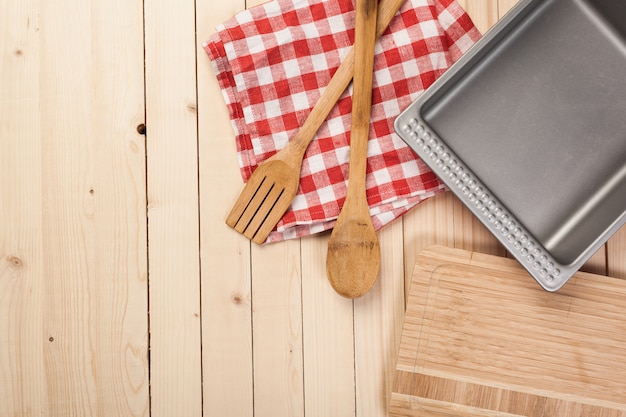 Cucchiai di legno e altri strumenti di cottura con tovaglioli rossi sul tavolo della cucina.