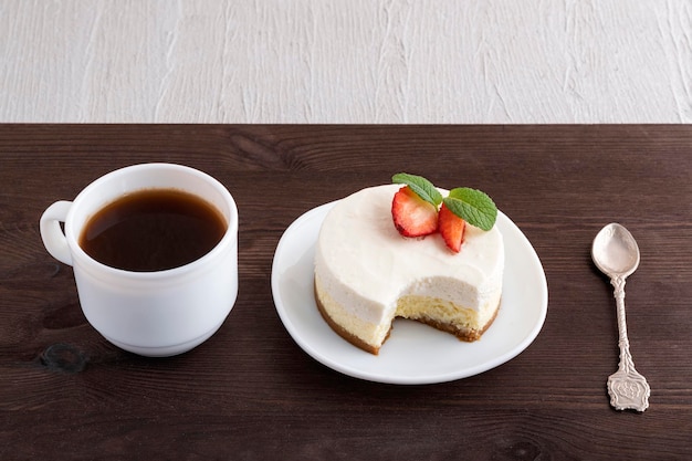 Cucchiaino di cheesecake e tazza di caffè su fondo di legno scuro Dessert nella caffetteria