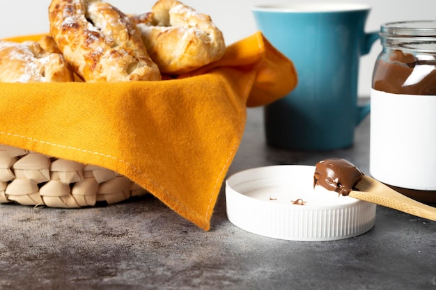 Cucchiaio al cioccolato per spalmare le sfogliatine napoletane. Barattolo pieno di cioccolato accanto a un caffè