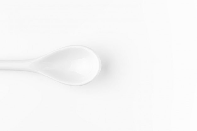 Cucchiaio bianco isolato su una superficie bianca