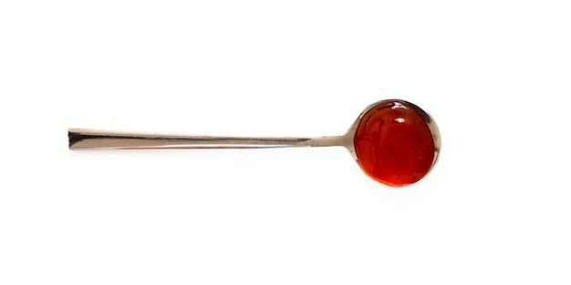 Cucchiaio con la salsa di peperoncino rosso dolce isolata su fondo bianco