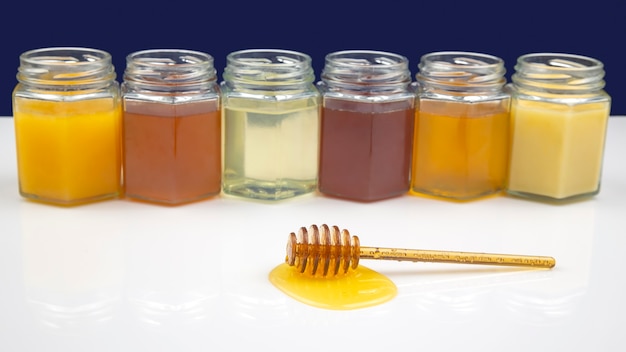 Cucchiaio con miele fresco e polline sullo sfondo di vasetti con diversi tipi di miele. cibo vitaminico biologico