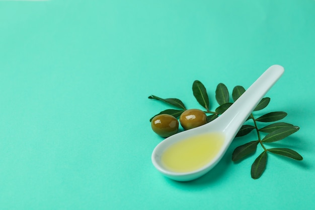 Cucchiaio con olio, olive e rametti su sfondo di menta