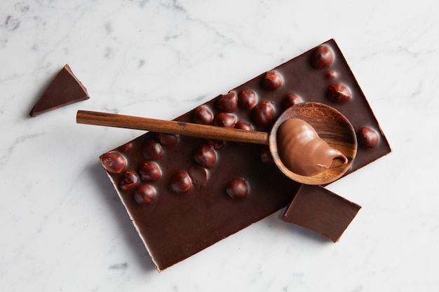 cucchiaio di legno con caramello su una tavoletta di cioccolato isolata su bianco