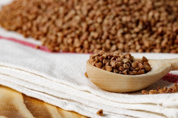 Cucchiaio di legno con la fine cruda del grano saraceno su