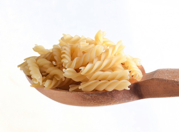 Cucchiaio di legno con la pasta di fusilli isolata